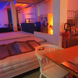 Winkelinterieur met bedden, tafels en stoelen onder paars en oranje verlichting
