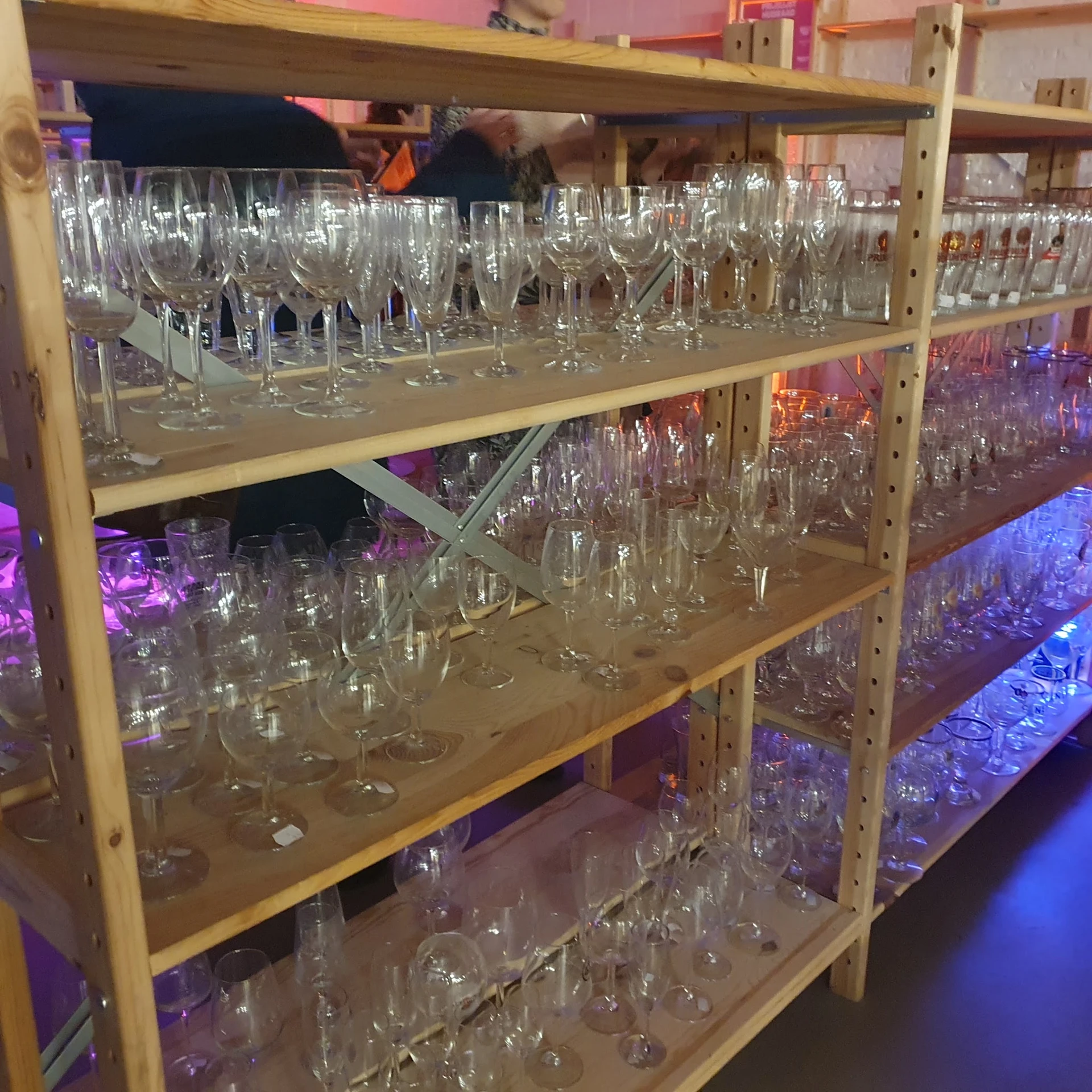 Metalen stellingen met honderden glazen drinkglazen en kristalglazen netjes uitgestald op meerdere niveaus