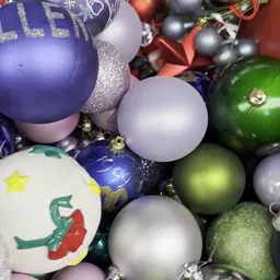 Verzameling kerstballen in verschillende kleuren en vormen, waaronder paarse, zilveren, groene en witte ballen met glitter en