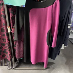 Rekken met tweedehands dameskleding in verschillende kleuren, waaronder roze, zwart en paarse kledingstukken