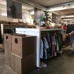 Winkelinterieur met kledingrekken, verrijdbare stellingen en uitgestalde tweedehands kleding