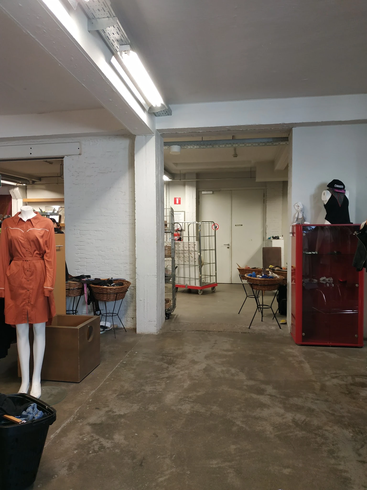 Winkelvloer met kledingrekken, stellingen, mannequin en diverse spullen in kringloopwinkel