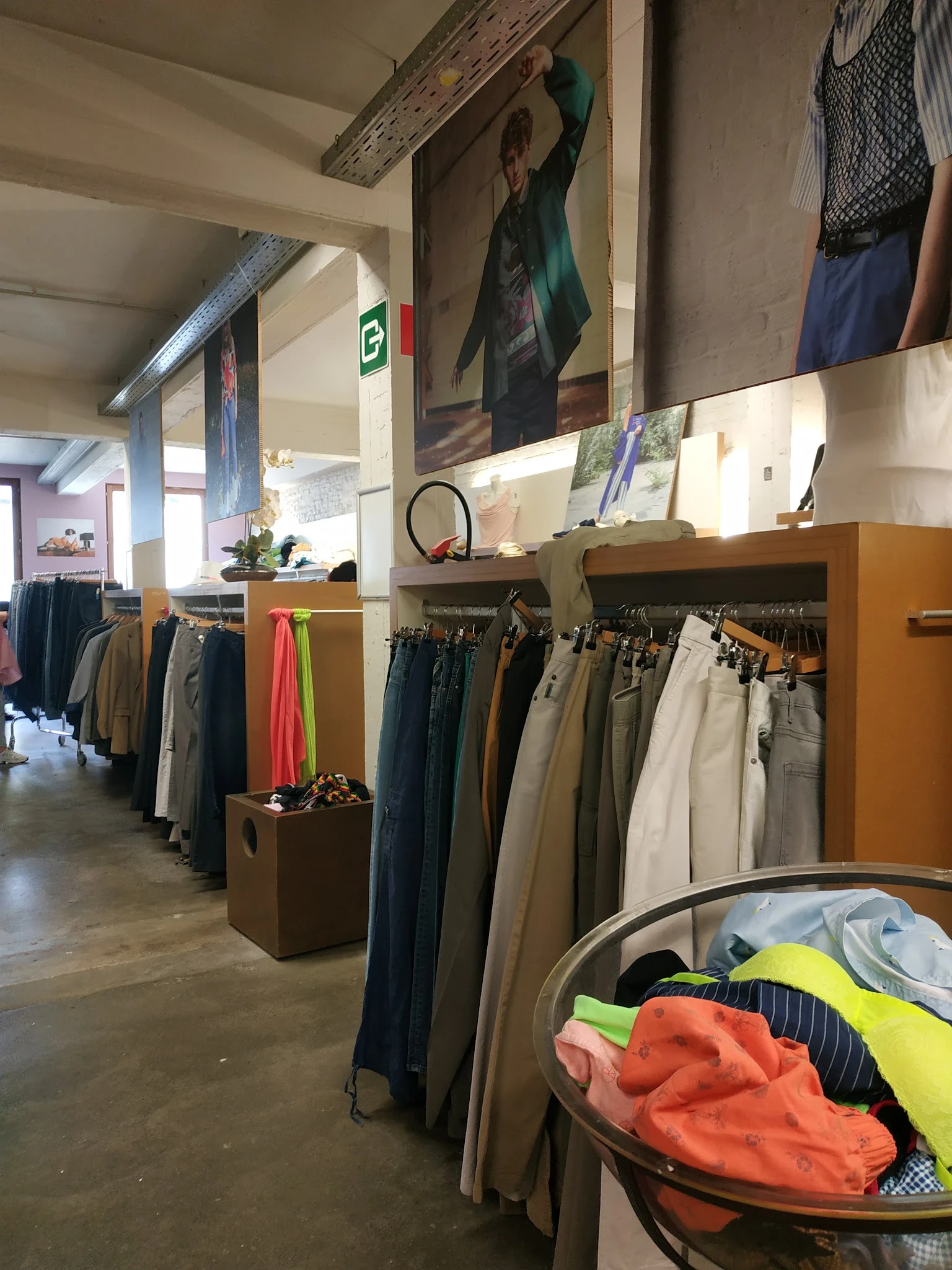Rekken met tweedehands broeken en kleding in verschillende kleuren georganiseerd in de winkel
