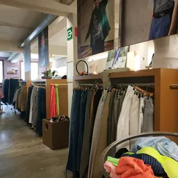 Rekken met tweedehands broeken en kleding in verschillende kleuren georganiseerd in de winkel