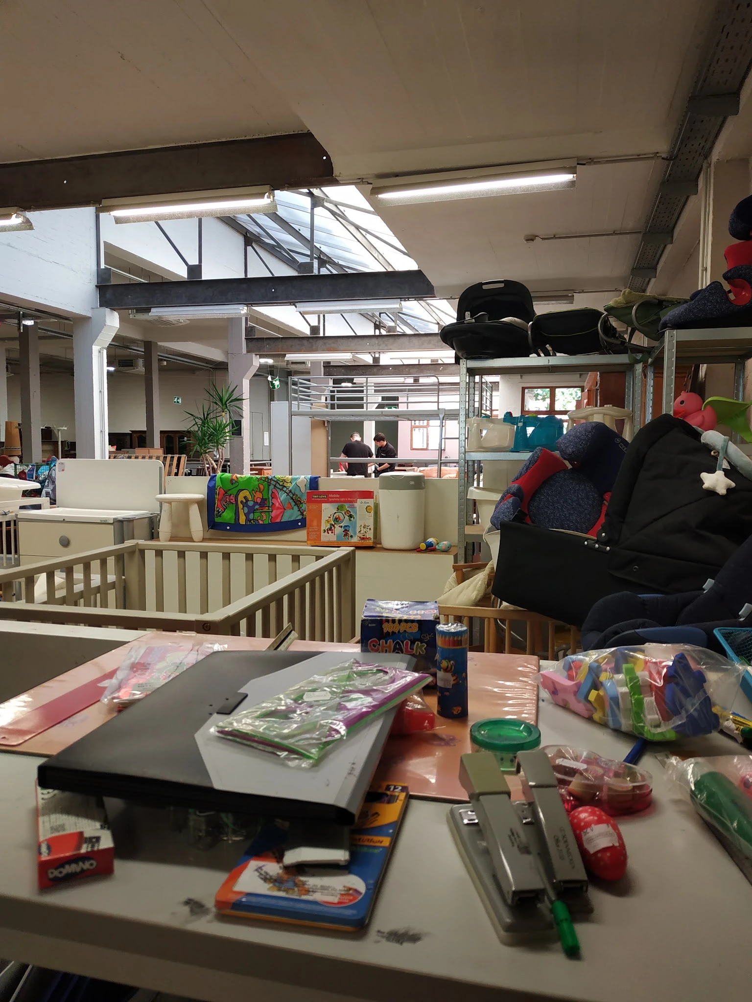 Winkelvloer met speelgoed, boeken en diverse artikelen, babybox en stellingen zichtbaar