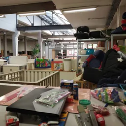 Winkelvloer met speelgoed, boeken en diverse artikelen, babybox en stellingen zichtbaar