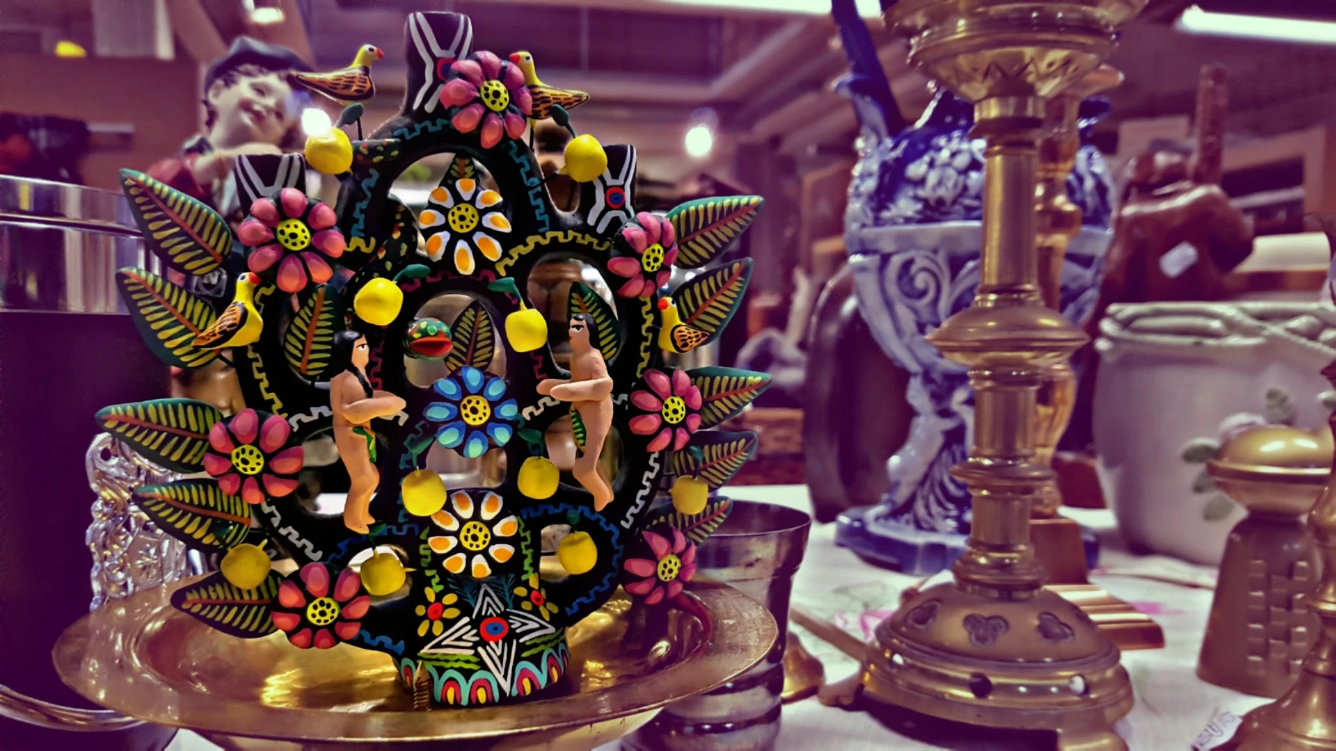 Kleurrijk versierde houten decoratief object met bloemen, figuren en sieraden op donkere ondergrond