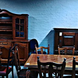 Tweedehands houten meubels uitgestald: antieke kasten, stoelen en tafels tegen blauwe muur