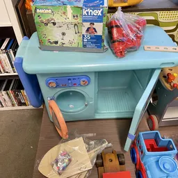 Speelgoed wasserette set in lichtblauw met wasmachine en droger, opgesteld in een winkelruimte