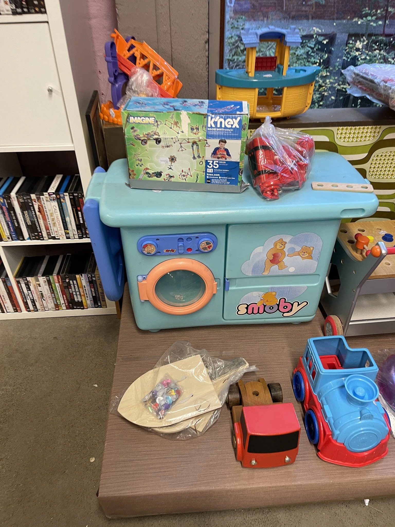 Speelgoedkeuken in turquoise met accessoires en boeken op achtergrond in kringloopwinkel