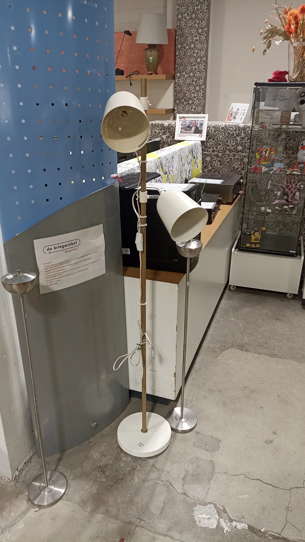 Winkelinterieur met stellingen, lampen en diverse artikelen; blauwe wand en textielstukken zichtbaar
