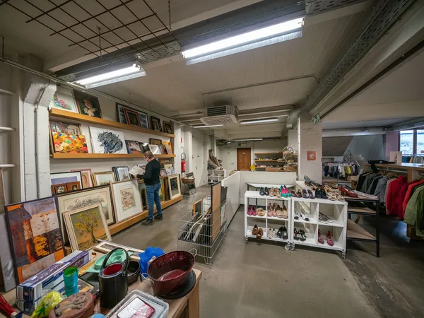 Winkelvloer van kringloopwinkel met stellingen, uitgestalde kunst, kleding en huishoudelijke spullen