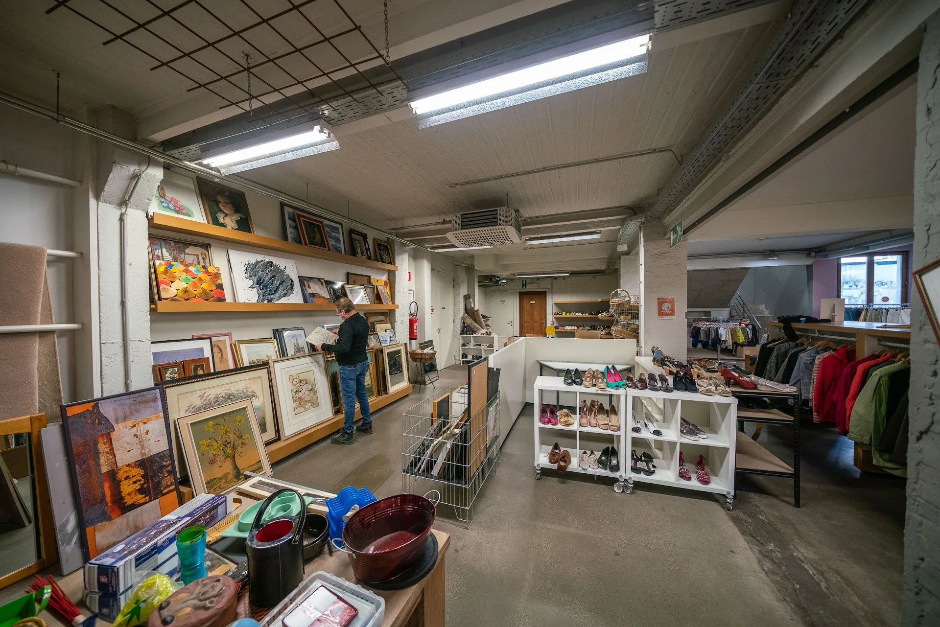 Winkelvloer van kringloopwinkel met stellingen, uitgestalde kunst, kleding en huishoudelijke spullen