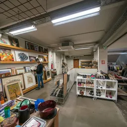Winkelvloer van kringloopwinkel met stellingen, uitgestalde kunst, kleding en huishoudelijke spullen