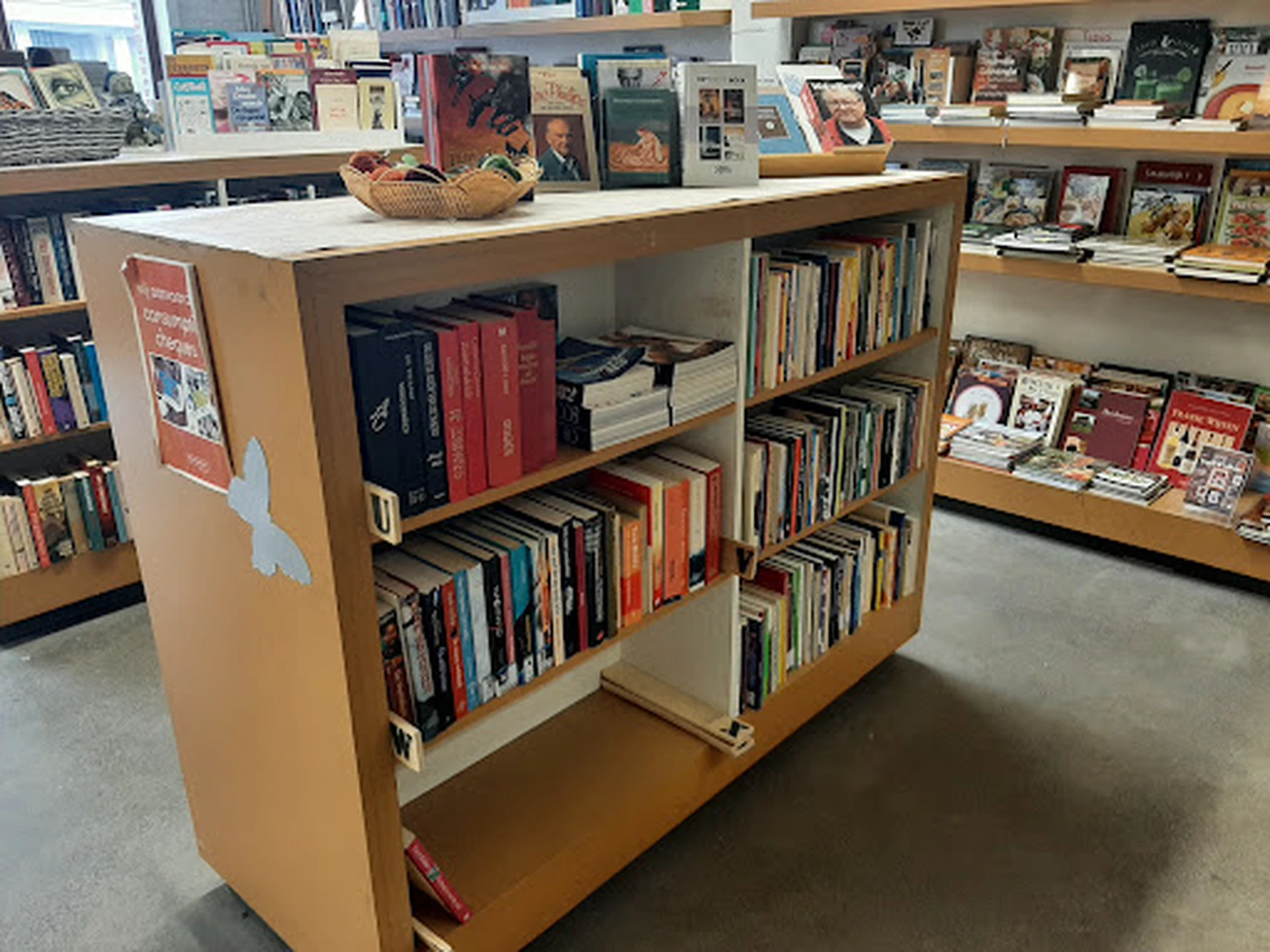 Houten boekenkasten op wielen gevuld met tweedehands dvd's, cd's en boeken in de winkel