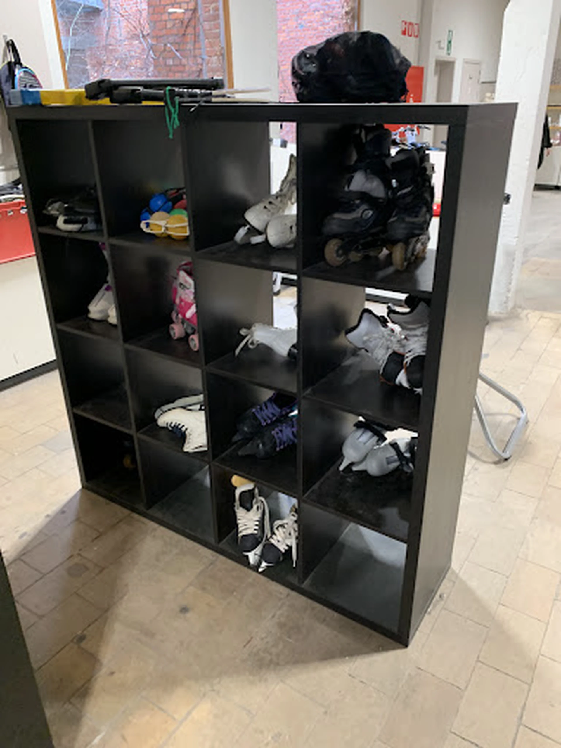 Zwarte stellingkast met 16 vakken vol met tweedehands schoenen en sportschoenen