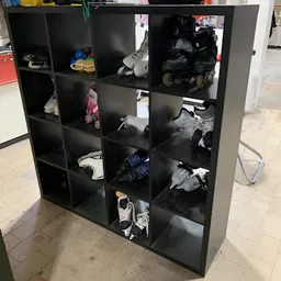 Zwarte stellingkast met 16 vakken vol met tweedehands schoenen en sportschoenen