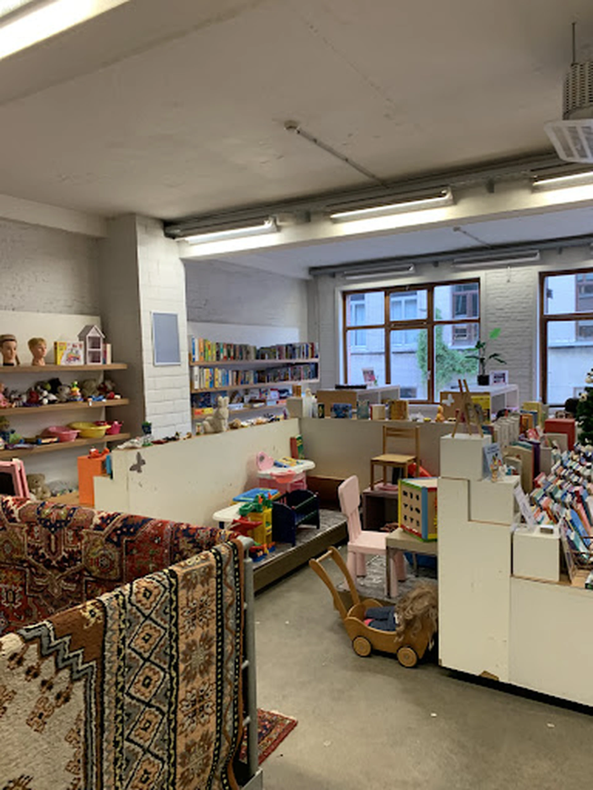 Ruim interieur van kringloopwinkel met speelgoed, boeken, meubels en diversen op stellingen en in dozen