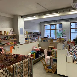 Ruim interieur van kringloopwinkel met speelgoed, boeken, meubels en diversen op stellingen en in dozen
