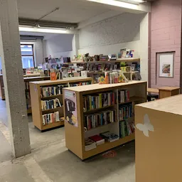 Winkelvloer met houten boekenkasten en stellingen vol tweedehands boeken en media