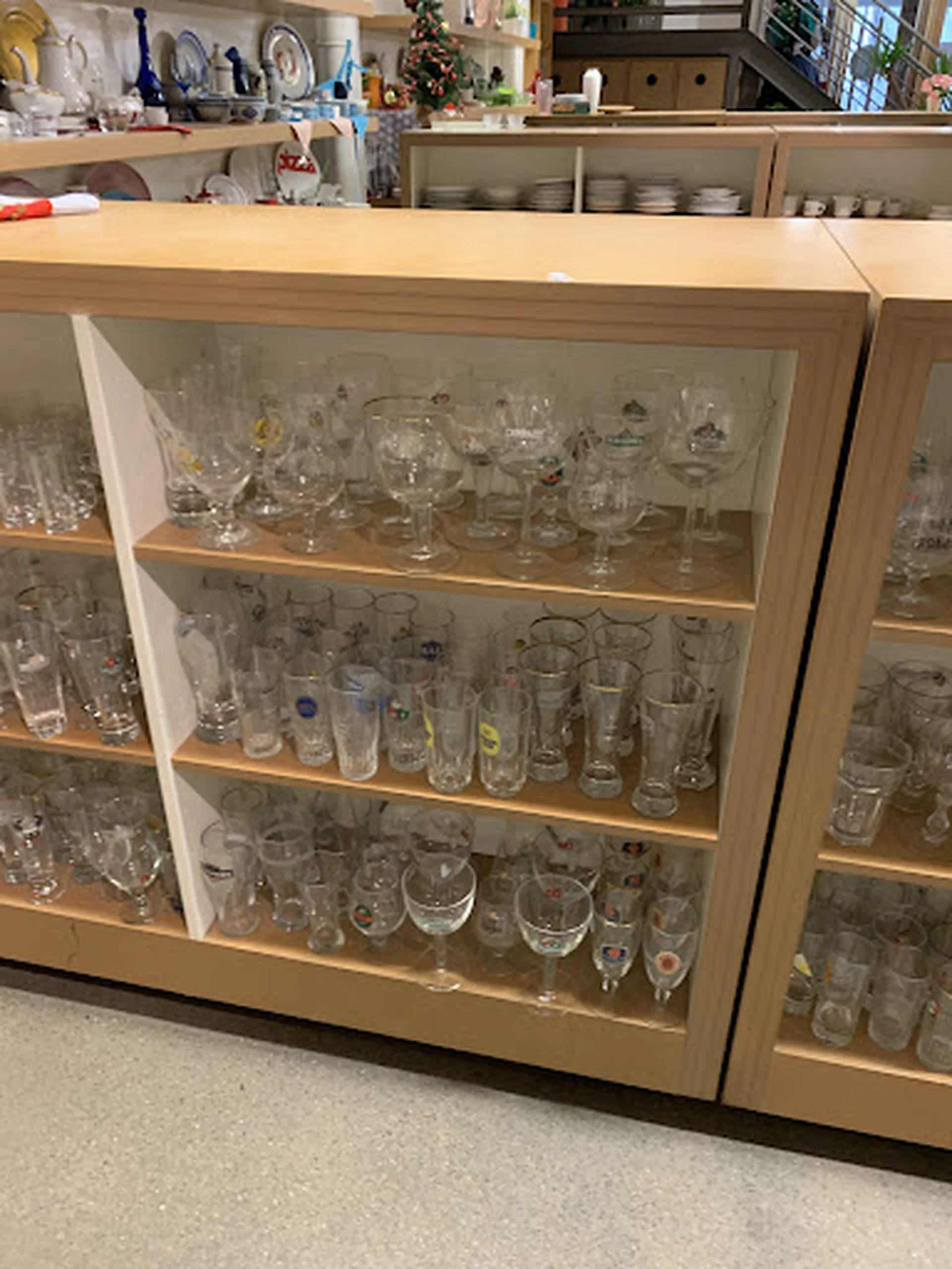 Glazenkast met diverse glaswerk en serviesgoed netjes uitgestald op houten planken
