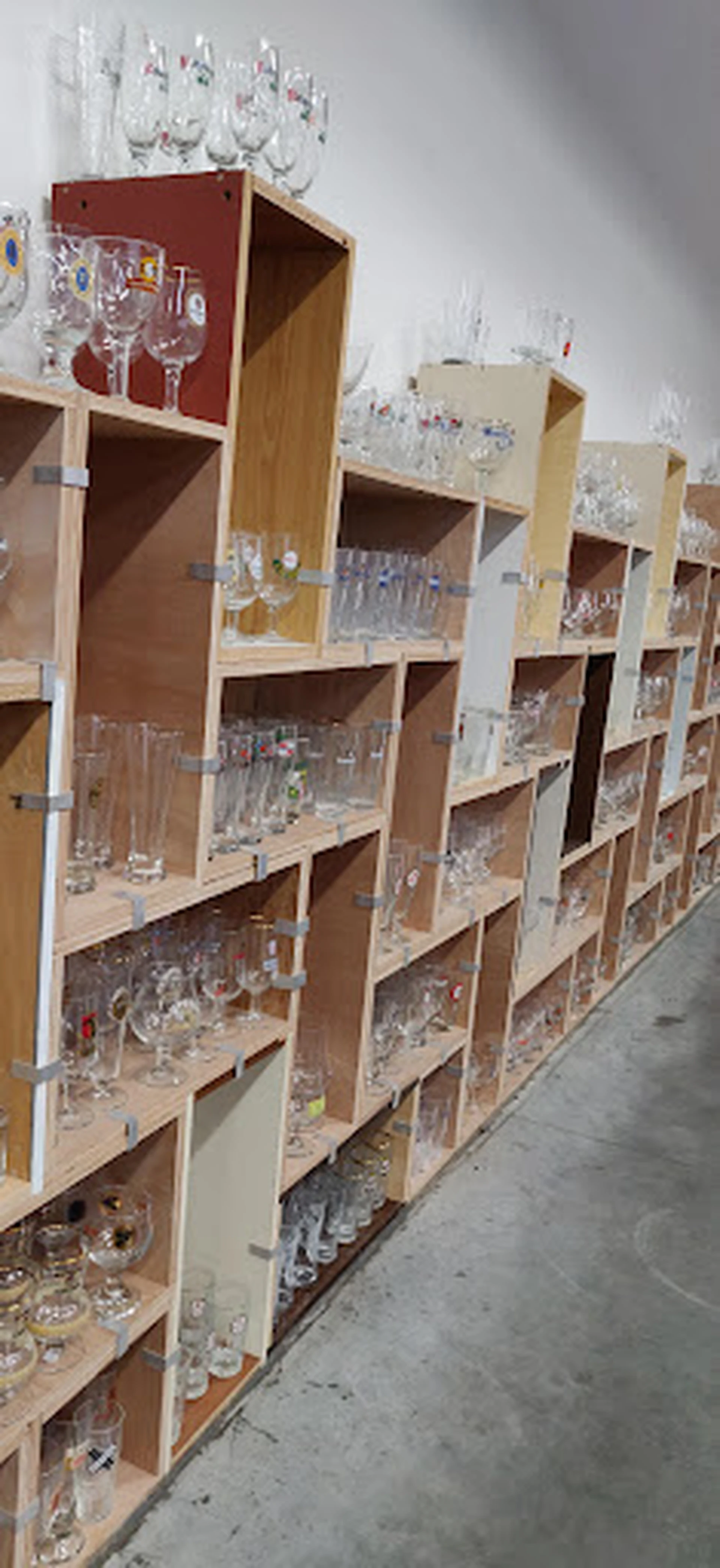 Houten stellingen met glazen servies, bekers en drinken glas uitgestald in een kringloopwinkel