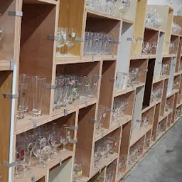 Houten stellingen met glazen servies, bekers en drinken glas uitgestald in een kringloopwinkel