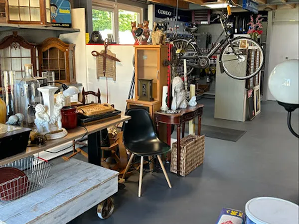 Kringloopwinkelinterieur met meubels, fiets aan muur, vintage items en dozen