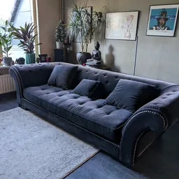 Donkerblauwe chesterfield-bank met kussens en decoratie in winkelinterieur