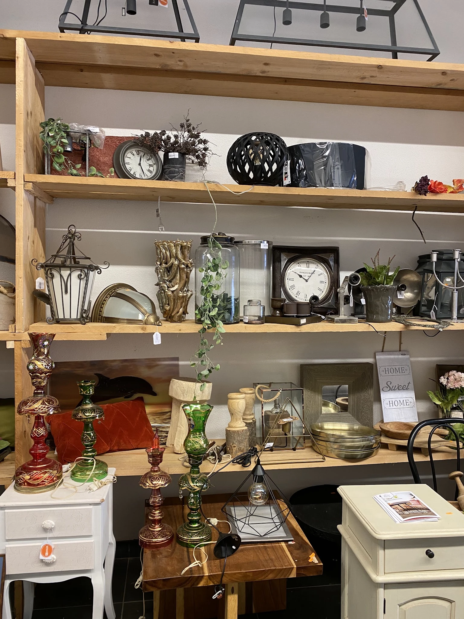 Houten wandplanken met verzameling vintage huishoudartikelen, klokken, kandelaars, bloemen en decoratieve items