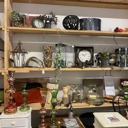 Houten wandplanken met verzameling vintage huishoudartikelen, klokken, kandelaars, bloemen en decoratieve items