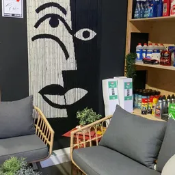 Winkelinterieur met grijze fauteuils, zwart-wit kunstwerk aan muur, houten plantenbak en houten planken met diverse producten
