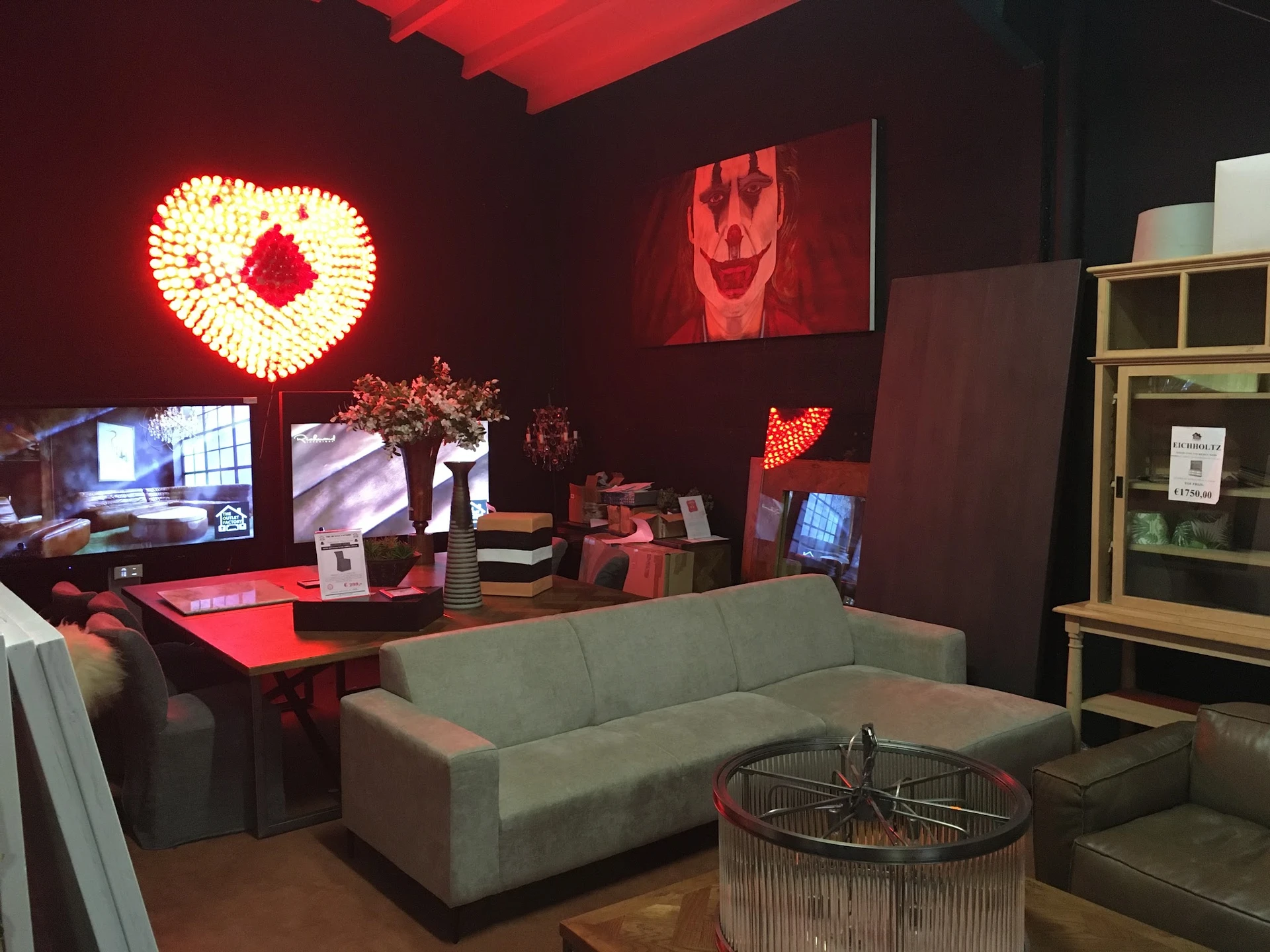 Winkelinterieur met grijze bank, rode bureau, neonverlichting en houten kasten met diverse spullen