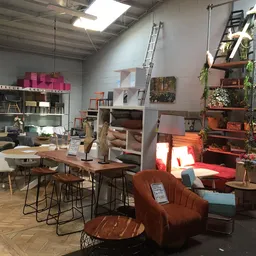 Vintage winkelbinnenruimte met meubels, planken, decoratie en verlichte zithoek met bruine fauteuil