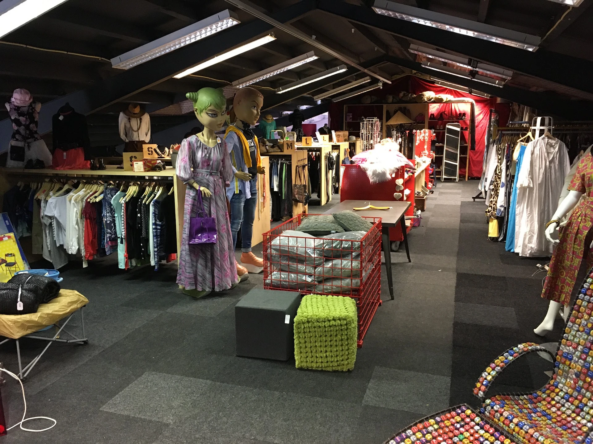 Ruim winkelinterieur met kledingrekken, etalagepoppen in vintage kleding en diverse spullen uitgestald