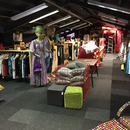 Ruim winkelinterieur met kledingrekken, etalagepoppen in vintage kleding en diverse spullen uitgestald