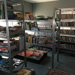 Winkelvloer met metalen stellingen vol dvd's, cd's en boeken, met dozen op de vloer