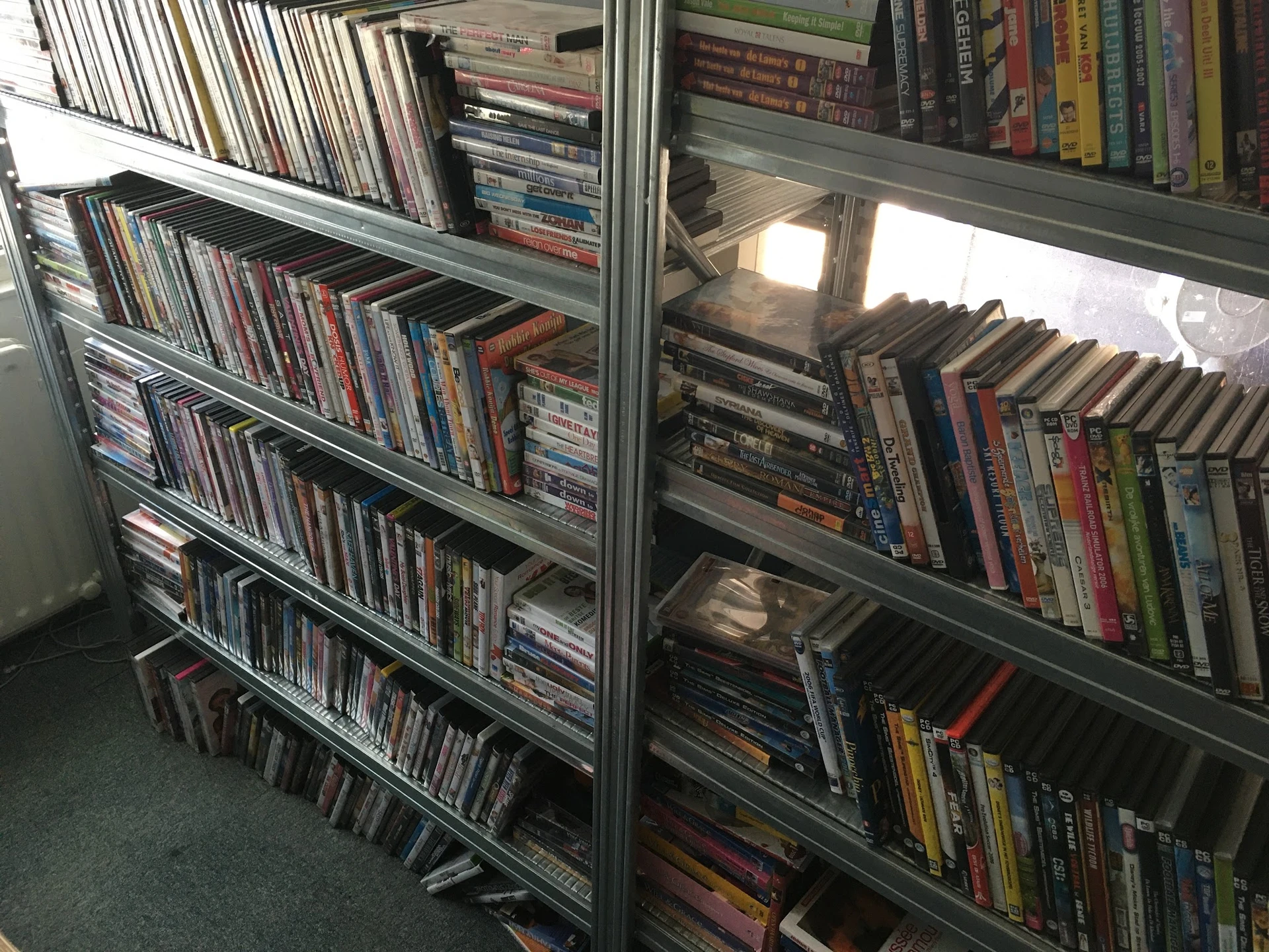 Glazen vitrinekasten met uitgestalde cd's en dvd's op meerdere niveaus