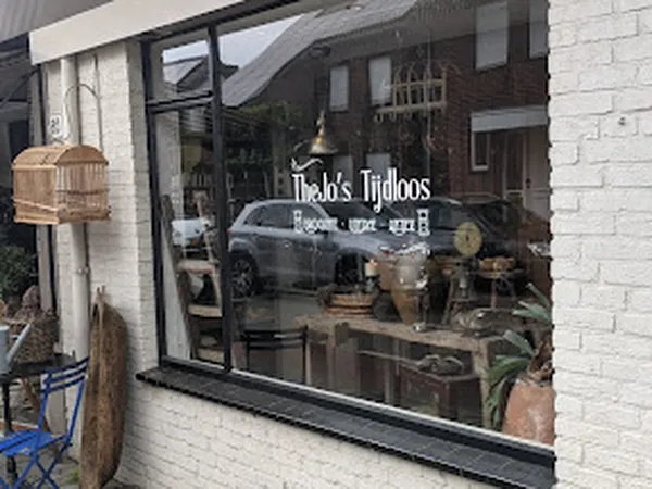 Winkelpui van TheJo's Tijdloos met zwarte aluminium raamkozijn, winkelnaam op raam, witte bakstenen gevel en straatmeubilair
