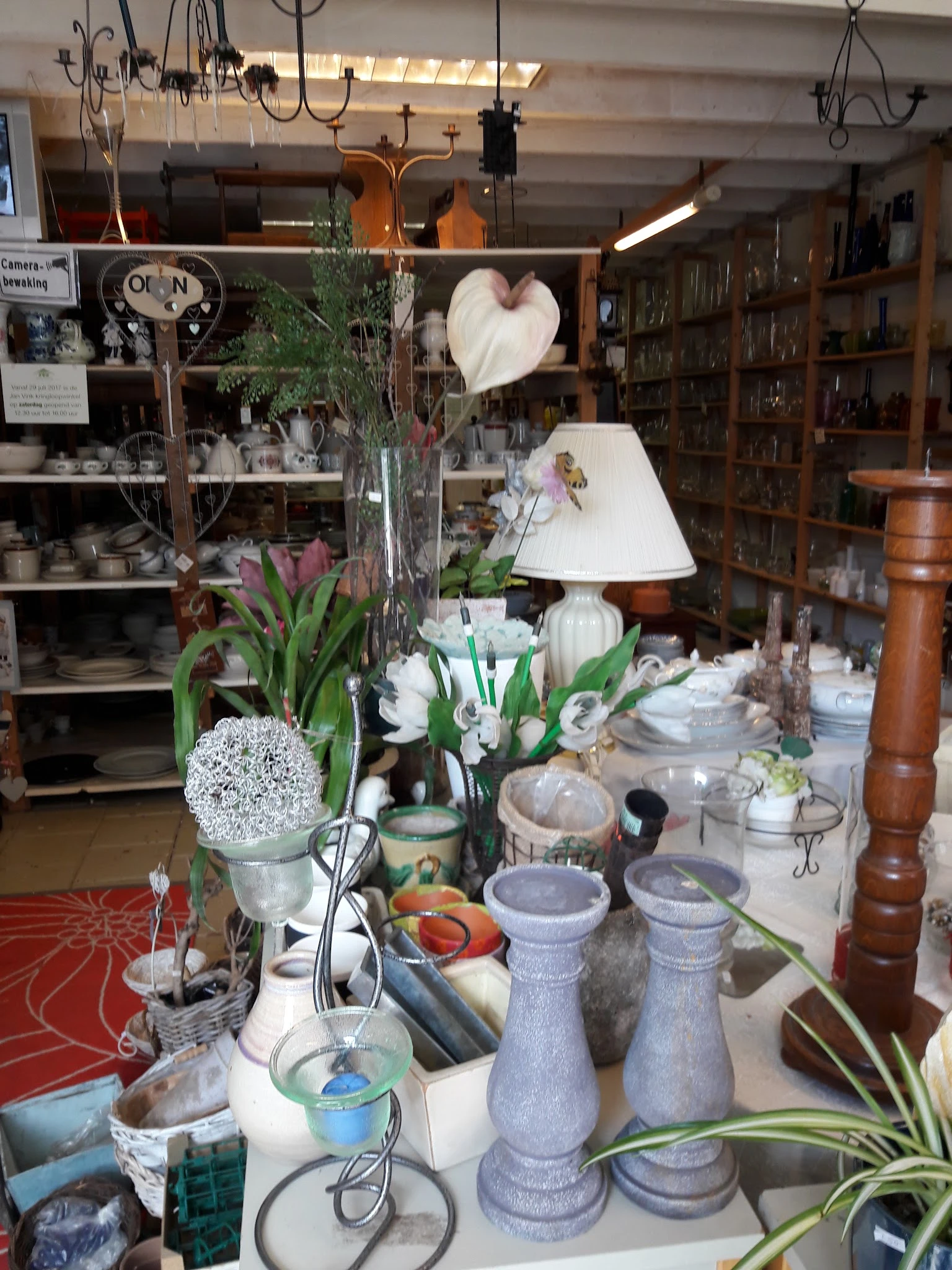 Uitgestalde huishoudartikelen, bloemen, lampen en decoratieve voorwerpen op een tafel in de winkel