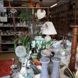 Uitgestalde huishoudartikelen, bloemen, lampen en decoratieve voorwerpen op een tafel in de winkel