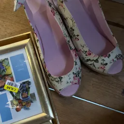 Paarse pantoffels met bloemenpatroon naast gouden fotolijst op houten vloer