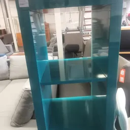 Turquoise/tealblauw houten boekenrek of displaykast met vier schappen, gefotografeerd in de winkel.