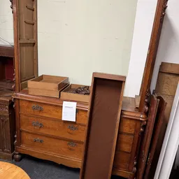 Tweedehands houten meubels uitgestald, waaronder dressoirs en kasten met metalen grepen