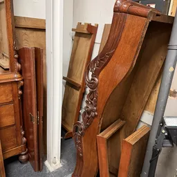 Verzameling tweedehands houten meubels en onderdelen, waaronder deuren, posten en decoratieve elementen met houtsnijwerk