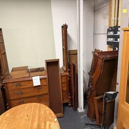 Houten meubels uitgestald in de winkel: dressoirs, kastjes, tafels en planken in verschillende kleuren hout