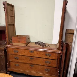 Houten ladekast met spiegelboven, bruine hardwarebeslag en enkele dozen op het blad