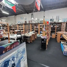 Winkelvloer met houten stellingen vol boeken, spullen en diverse tweedehands artikelen; vlaggen aan plafond