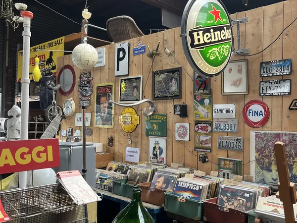 Winkelmuur met verzameling vintage spullen: neonreclames, nummerborden, oude foto's, decoratieve borden en andere antieke obj