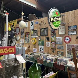 Winkelmuur met verzameling vintage spullen: neonreclames, nummerborden, oude foto's, decoratieve borden en andere antieke obj